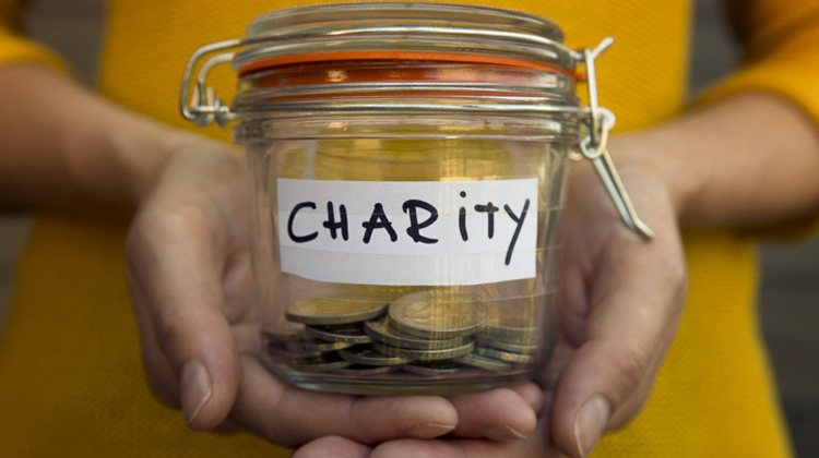 Person holding charity jar with coins Person holding charity jar with coins