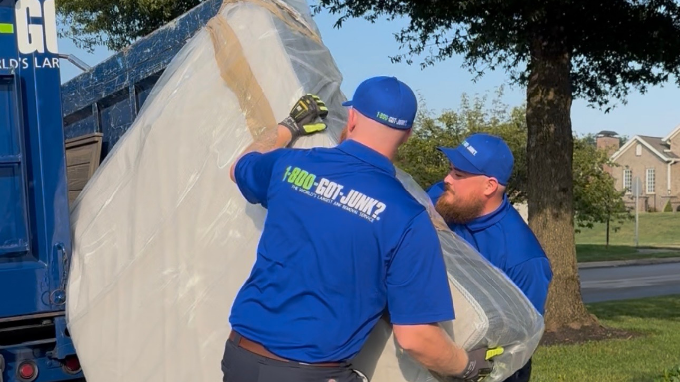 Two 1-800-GOT-JUNK? Truck Team Members lifting a mattress into the truck. Two 1-800-GOT-JUNK? Truck Team Members lifting a mattress into the truck.