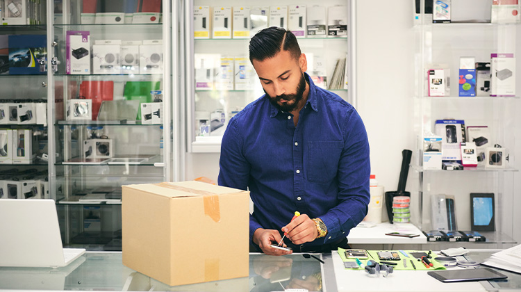 Proper disposal of old phones and electronics A man packing old phones and electronics in a box for proper disposal