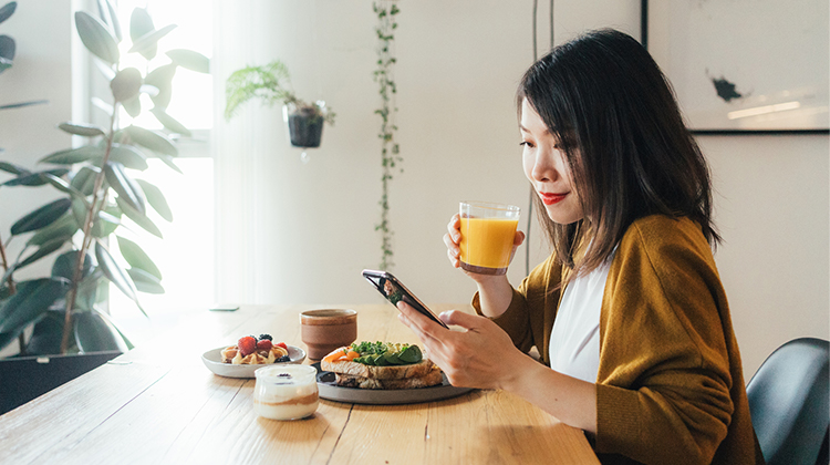 Woman having brunch while looking at her phone Woman having brunch while looking at her phone